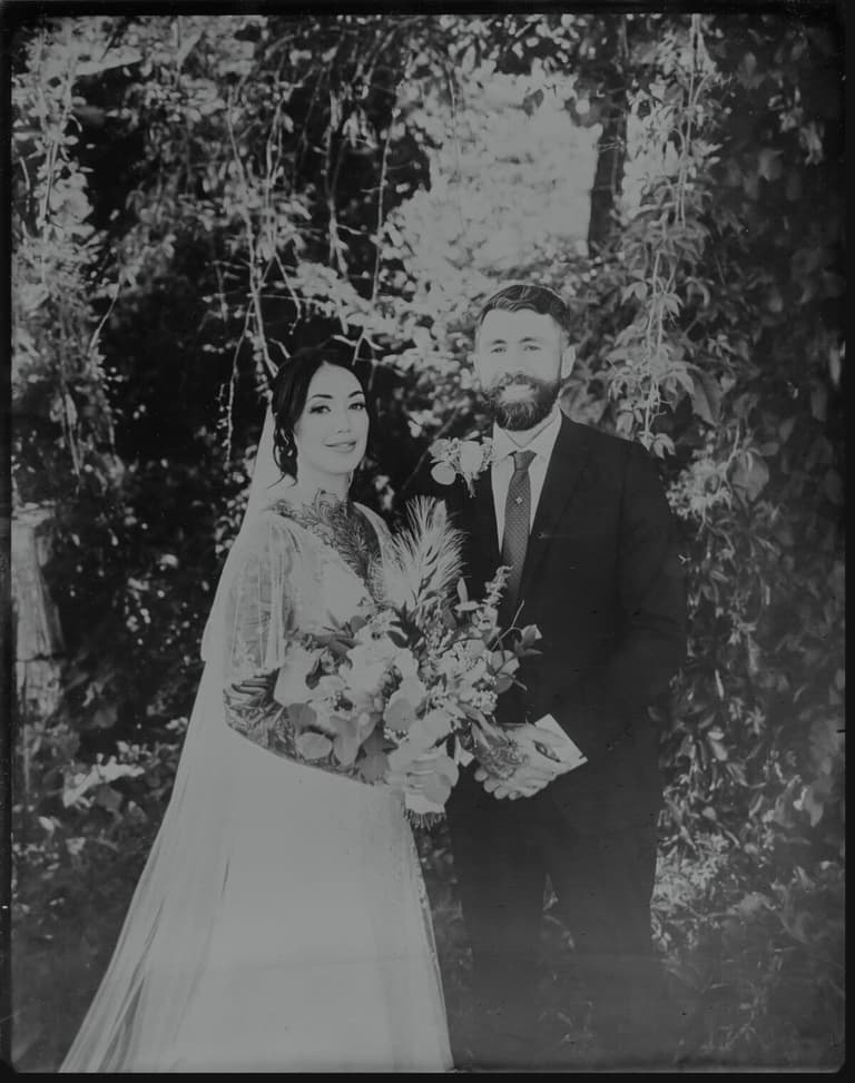 Tintype of smiling newlyweds beneath trailing vines