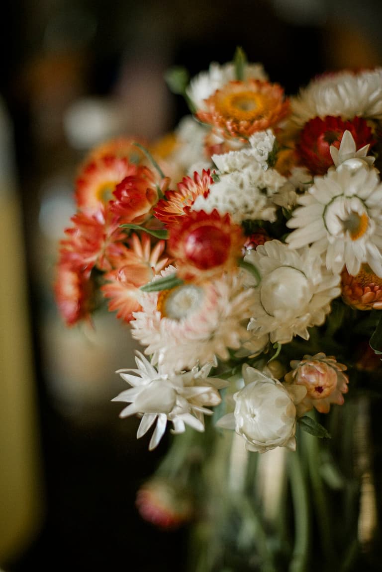 Strawflowers and daisies in an orange-and-white bridal bouquet