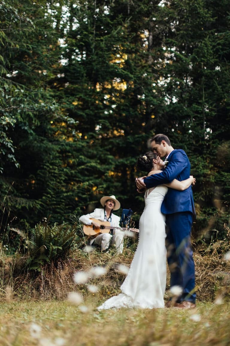 Oliver Swain playing guitar for a couple's forest first dance