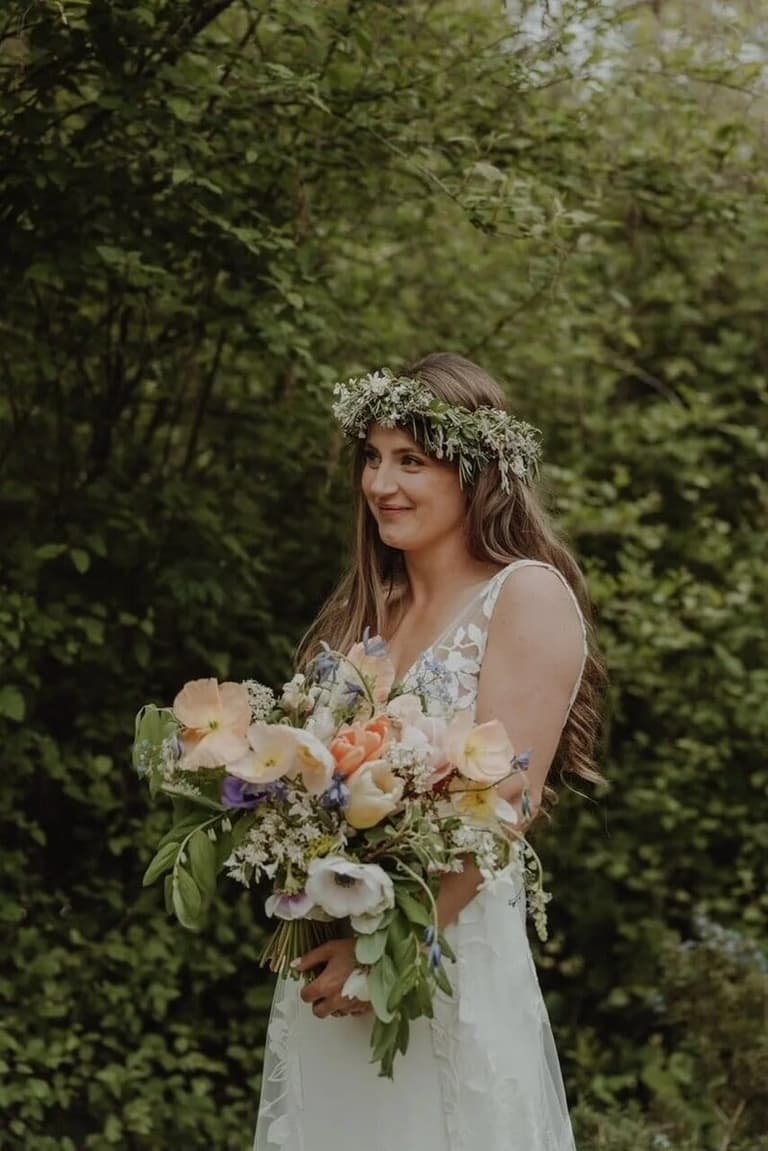 Bride in a flower crown holding a pastel Sea of Blooms bouquet