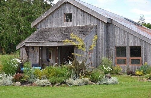 Weathered barn exterior and gardens at The Barn Suite, Little Tribune Bay