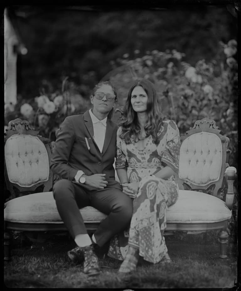 Couple seated close on a Victorian settee in the rose garden