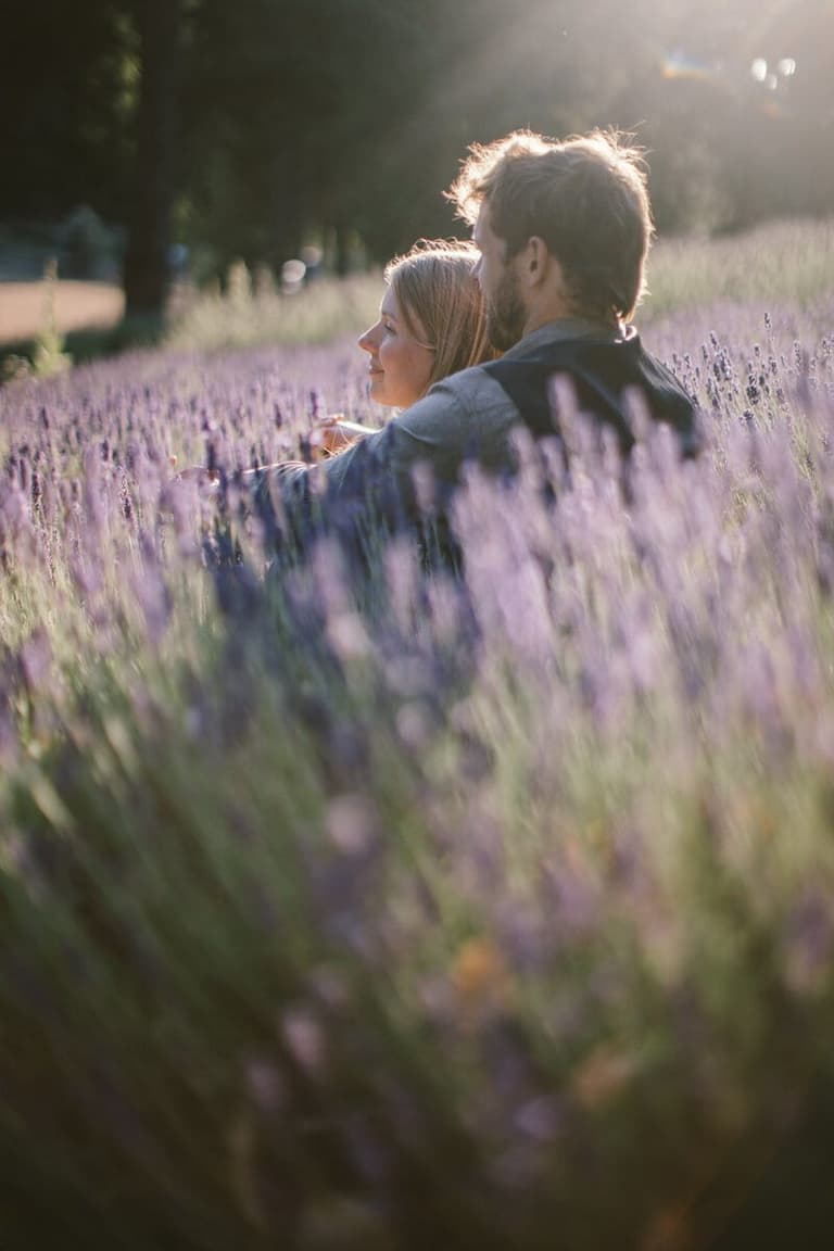Couple nestled together in a sunlit lavender field