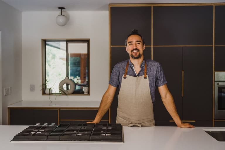 Chef Haan Palcu-Chang smiling behind a kitchen island cooktop