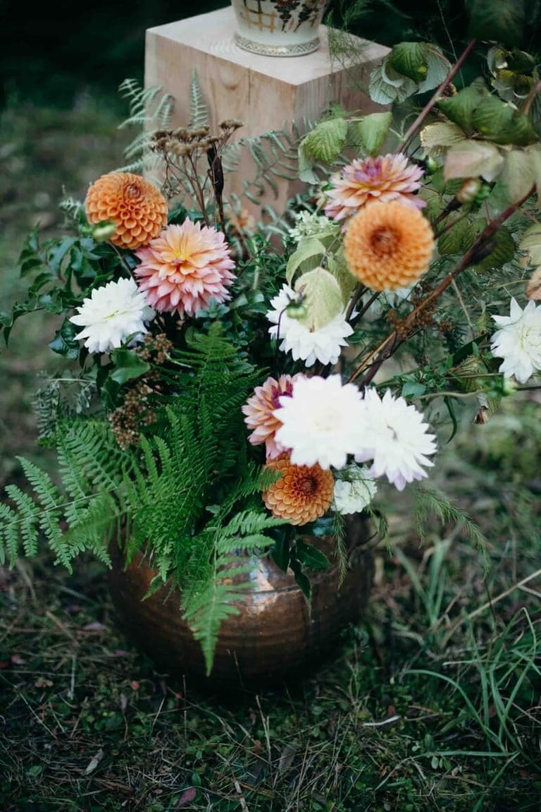 Copper vase of dahlias and ferns styled by Folklore Wedding Company