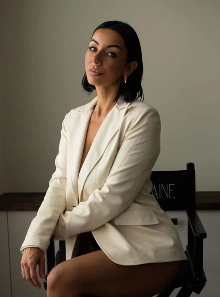 Makeup artist Chloe Lorraine seated in a cream blazer
