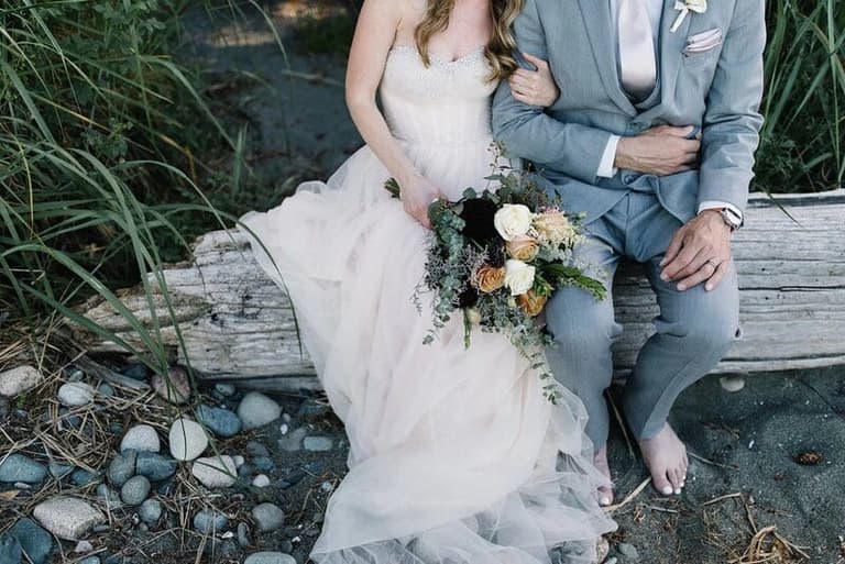 Muted peach Evoke Floral bouquet held by a bride on driftwood