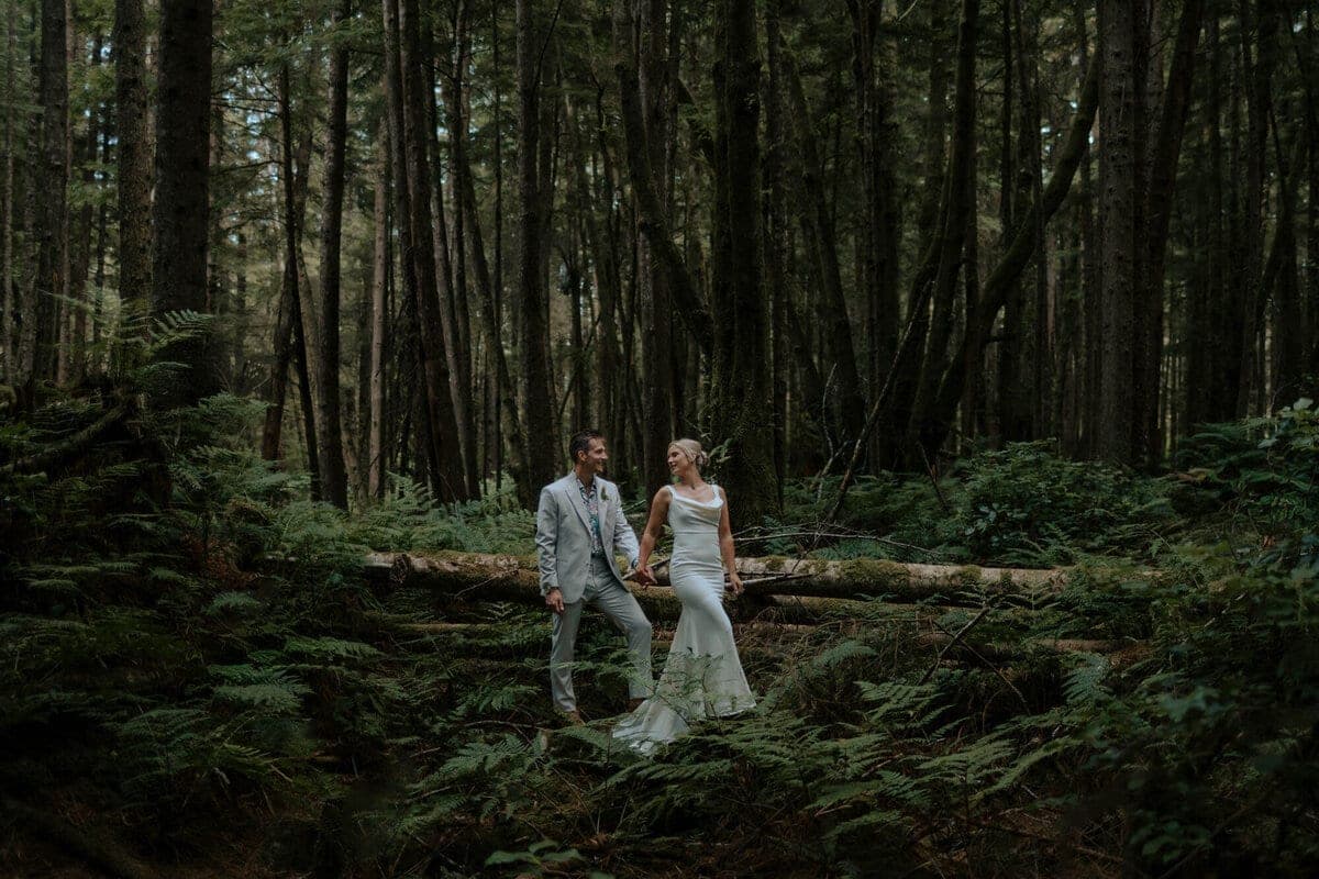 Bride and groom holding hands in a mossy island forest