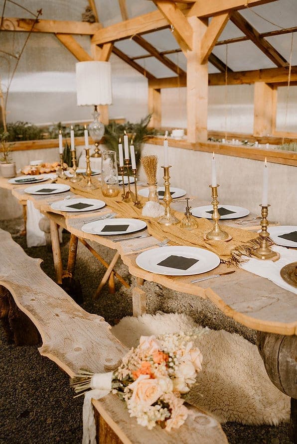 Candlelit live-edge banquet table inside the Grow Wild Retreats greenhouse