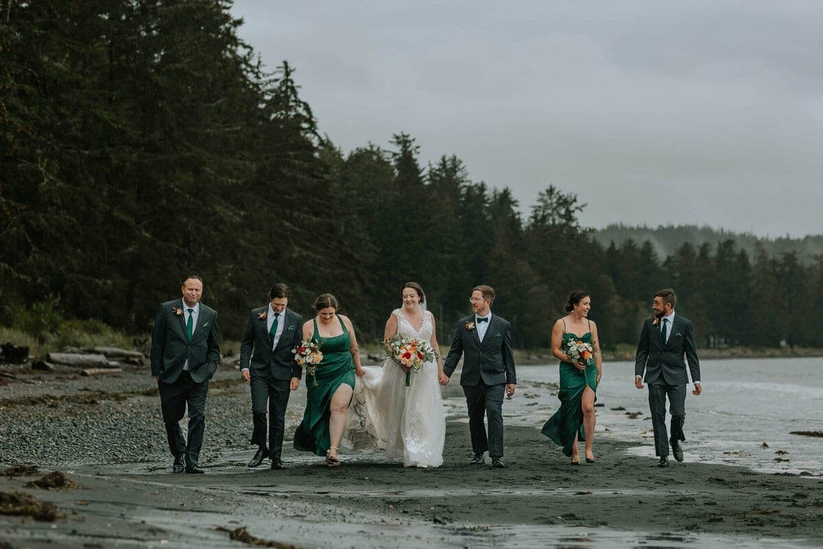 Wedding party in green and navy walking a pebbled north island beach