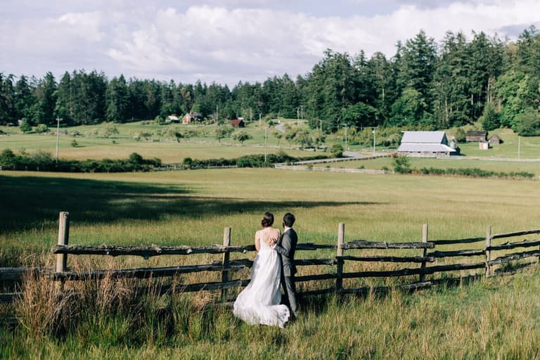 Bride and groom at a split-rail fence overlooking Ruckle Farm pastures