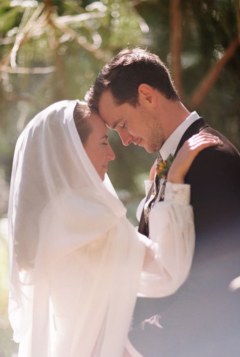 bride singing at the microphone while a guitarist plays under the tent