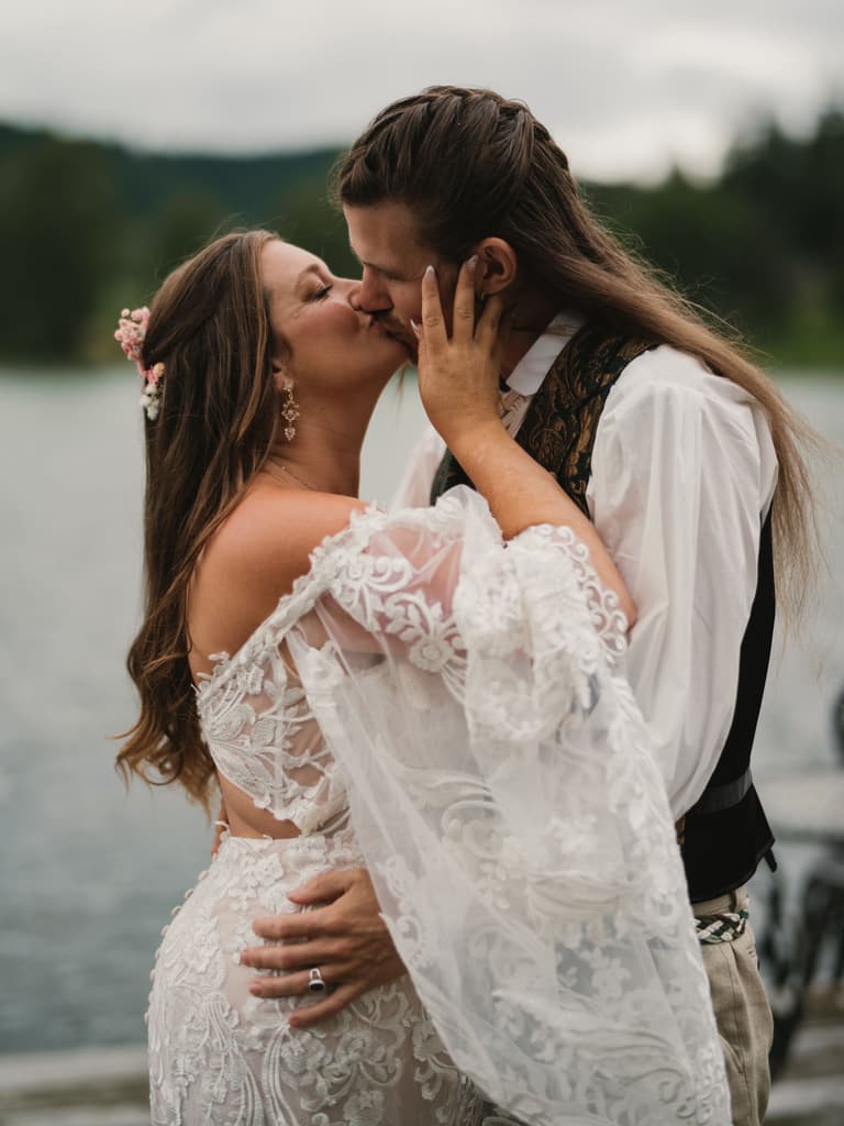 Bride and groom kissing amid sunlit grapevine leaves